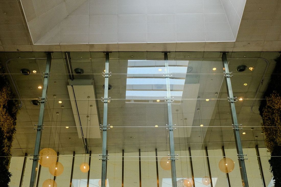 A bright atrium with a full-height glass wall and hanging lights